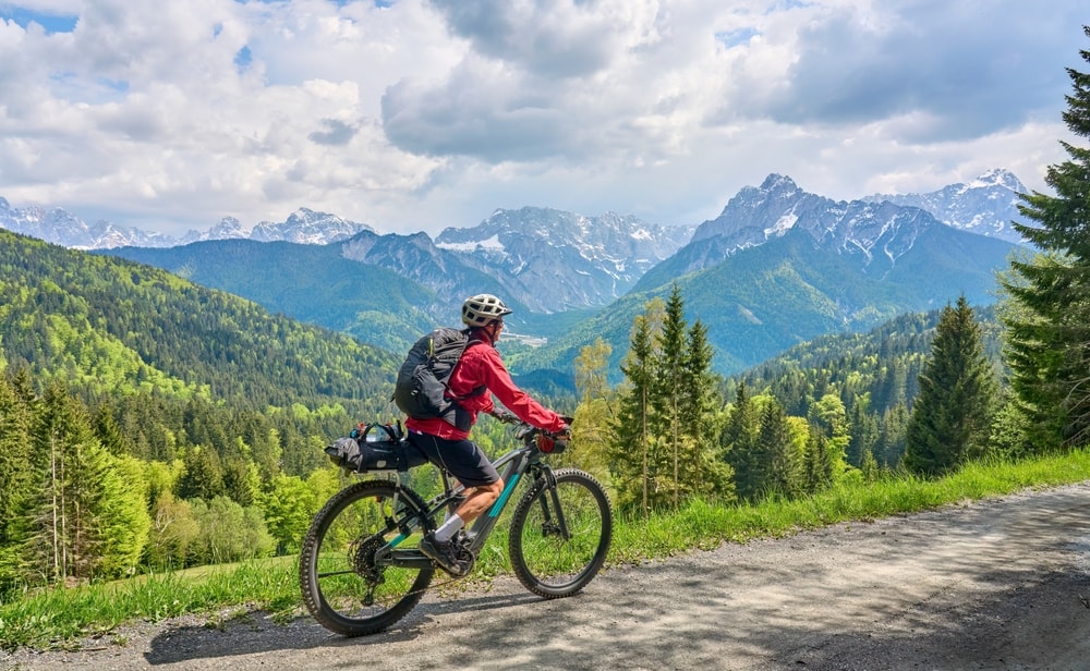 Cyclist riding a mountain bike through an Alpine landscape with snow-capped peaks