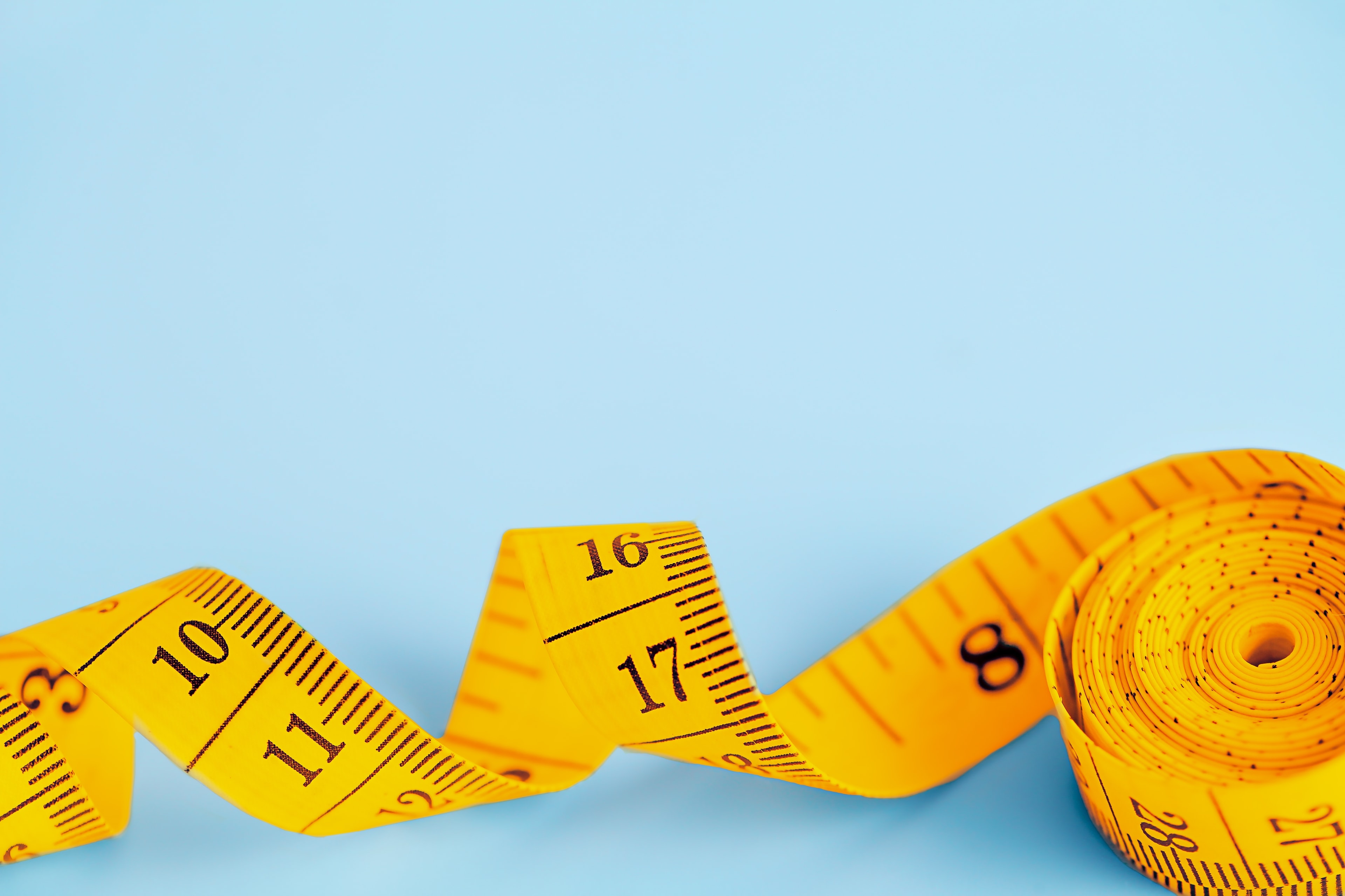 Yellow measuring tape on light blue background