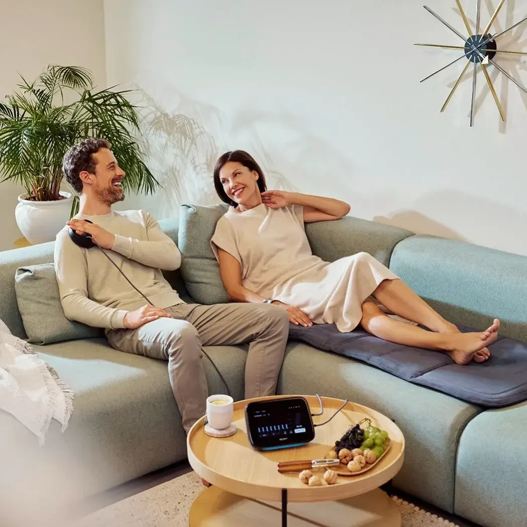 Couple relaxing on couch using BEMER PEMF mat